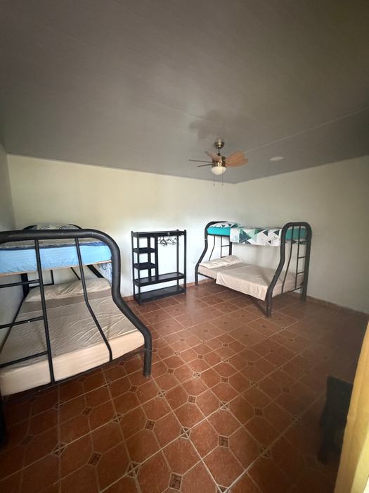 Habitación amplia con dos camarotes, un estante y ventilador de techo